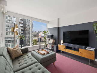 Experience modern urban living in this stylish apartment featuring a spacious living area with a large sectional sofa and a tufted ottoman.