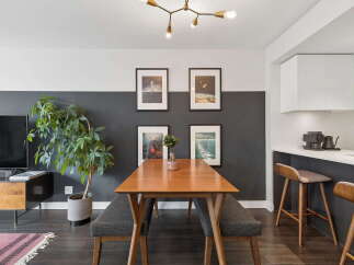 This modern dining area features a sleek wooden dining table with two upholstered benches, perfect for intimate meals.