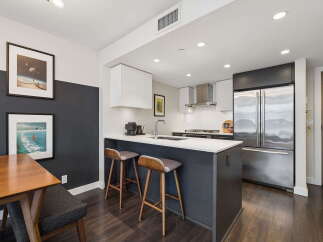 Experience modern living in this stylish kitchen featuring a sleek dark island with bar seating, perfect for casual dining or entertaining.