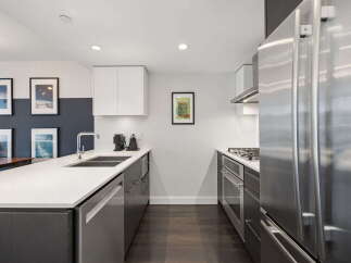 Experience modern living in this sleek kitchen featuring stainless steel appliances, a spacious island with a double sink, and ample cabinet space.