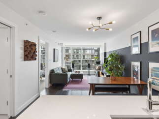This modern living and dining area features a stylish gray sofa with an ottoman, complemented by a sleek wooden dining table and bench.