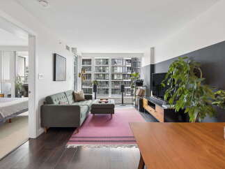 Experience modern urban living in this stylish apartment featuring a spacious living area with a comfortable sofa and ottoman, perfect for relaxation.