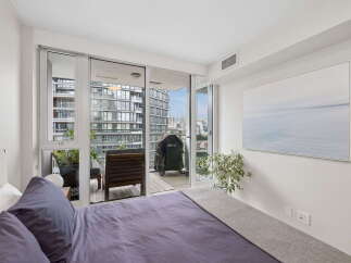 Experience urban living with this stunning bedroom featuring a private balcony overlooking the city skyline.