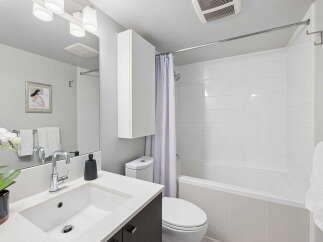 This modern bathroom features a sleek vanity with a vessel sink and chrome faucet, complemented by a large mirror with track lighting.