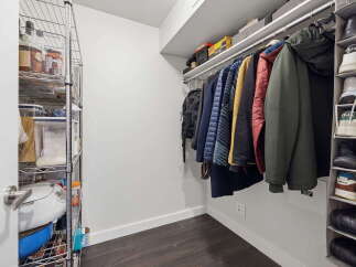 Maximize your storage with this well-organized closet featuring a multi-tiered shelving unit perfect for pantry items and a hanging rack for coats and jackets.