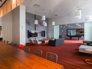 Experience modern living in this spacious common area, featuring a large communal dining table perfect for gatherings.