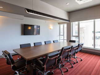 This modern conference room features a large, polished wood table surrounded by comfortable executive chairs, perfect for productive meetings.