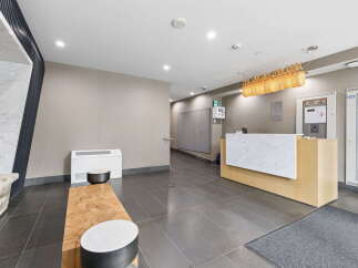 Step into a modern and inviting lobby featuring a sleek reception desk with a marble countertop, perfect for greeting guests.