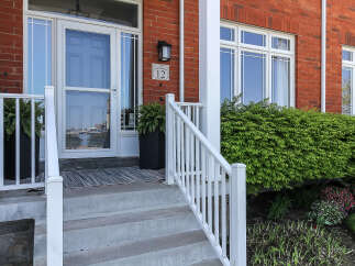 Welcome to this charming brick home featuring a classic front porch with a white railing and a welcoming entryway.