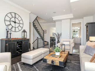 Step into this beautifully appointed living room, featuring a striking oversized wall clock and a stylish black buffet with a built-in wine rack.