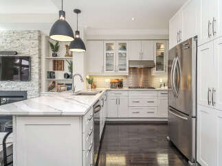 Experience luxury in this modern kitchen featuring sleek white cabinetry, a stunning marble island with a waterfall edge, and high-end stainless steel appliances.