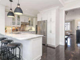 Experience luxury living in this stunning modern kitchen, featuring sleek white cabinetry, a spacious marble island with bar seating, and high-end stainless steel appliances.