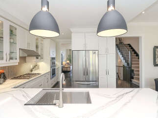 Experience luxury in this stunning modern kitchen, featuring sleek white cabinetry, a sophisticated gas range, and a large stainless steel refrigerator.