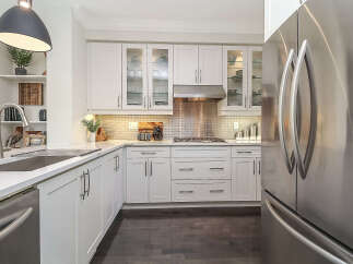 Experience modern living in this stunning kitchen, featuring sleek white cabinetry and a gleaming stainless steel refrigerator.