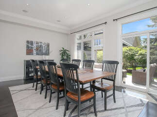 This elegant dining room features a large wooden table surrounded by black and wood chairs, perfect for family gatherings.