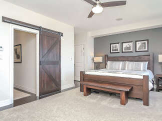Experience rustic charm in this master bedroom featuring a stunning barn door leading to an ensuite.