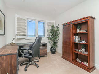 This home office features a spacious wooden desk with a modern black leather chair, perfect for productivity.