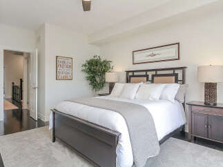 This inviting bedroom features a spacious dark wood bed adorned with crisp white linens and a textured grey throw.