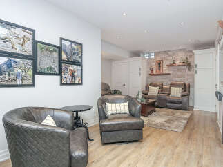 This inviting basement living area features comfortable leather seating, including two plush armchairs and a matching sofa, perfect for relaxation.