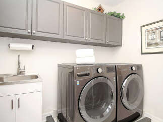 This laundry room features a sleek, modern design with ample storage provided by the gray upper cabinets.