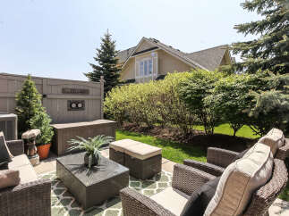 Enjoy outdoor living in this charming backyard featuring a comfortable seating area with a wicker sofa, coffee table, and ottomans, perfect for entertaining.
