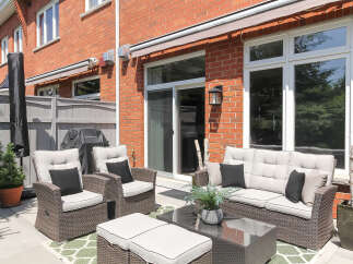 Enjoy outdoor living with this spacious patio featuring comfortable wicker furniture, a propane grill, and a stylish outdoor rug.