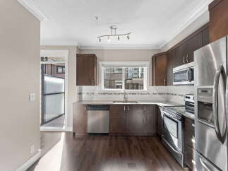 Discover this modern kitchen featuring dark wood cabinetry and sleek stainless steel appliances, including a refrigerator, dishwasher, and oven.