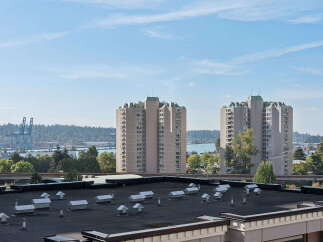 Experience breathtaking views from this high-rise apartment, offering panoramic vistas of the water, lush greenery, and distant industrial cranes.