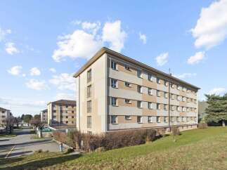 Discover modern living in this apartment complex featuring a striking facade with alternating beige and cream panels.