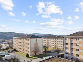 Discover modern living in this apartment building featuring a striking facade with alternating beige and white panels.