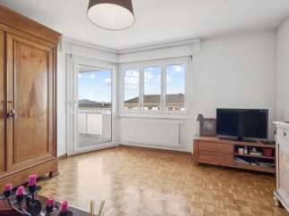 Discover this charming living room featuring a large wooden wardrobe and a TV stand with a flat-screen television.