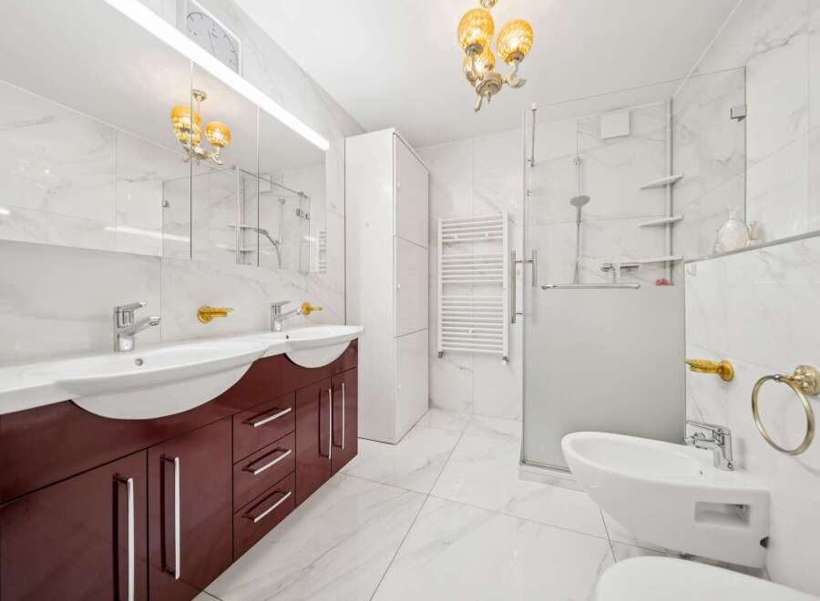 Experience modern luxury in this stunning bathroom featuring a double vanity with a rich, dark wood cabinet and sleek chrome fixtures.