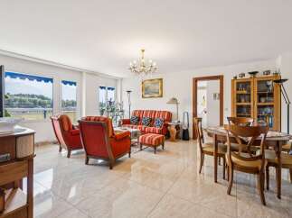 Experience elegant living in this spacious room featuring a vibrant red striped sofa and matching armchairs, complemented by a classic chandelier.