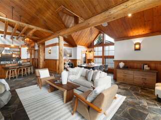 Experience rustic elegance in this stunning log home featuring a spacious open-concept living area with a vaulted wood-beamed ceiling and a modern kitchen island.