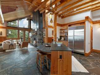 Experience rustic luxury in this stunning mountain home, featuring a grand stone fireplace and soaring log beam ceilings.