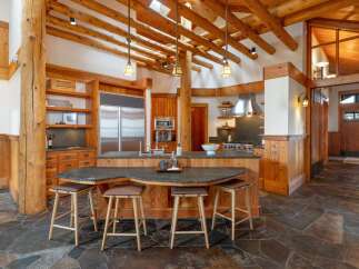 Experience rustic luxury in this stunning log cabin kitchen, featuring a large island with granite countertops and comfortable bar stools.