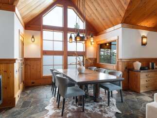 Experience rustic elegance in this dining room, featuring a grand wooden table and comfortable upholstered chairs set on a unique stone floor.