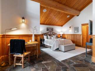 Experience rustic charm in this inviting bedroom featuring a cozy bed with plush pillows and a warm wood-paneled accent wall.