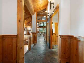 Experience rustic charm in this stunning log home hallway, featuring a grand wooden beam and a unique stone tile floor.