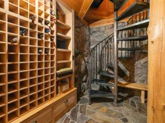 Discover this unique wine cellar featuring a rustic stone wall and a charming spiral staircase.