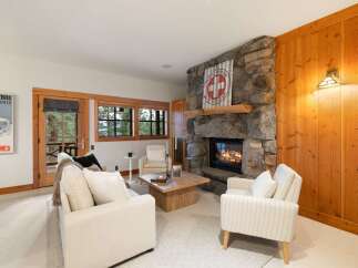 Cozy up by the stone fireplace in this inviting living room, perfect for après-ski relaxation.