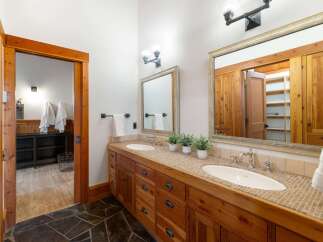 This rustic bathroom features a double vanity with a tiled countertop and wooden cabinetry, offering ample storage.