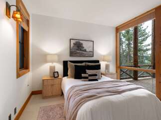Experience serene mountain living in this charming bedroom, featuring a plush bed adorned with cozy blankets and decorative pillows.
