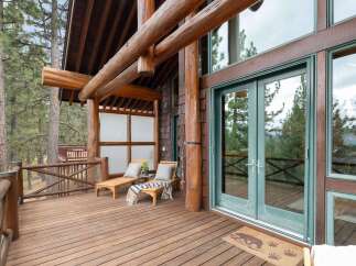 Experience rustic charm on this expansive wooden deck, featuring two inviting lounge chairs perfect for soaking in the serene forest views.