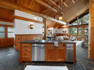 Experience rustic luxury in this stunning mountain home featuring a gourmet kitchen with a large island, stainless steel appliances, and ample wood cabinetry.