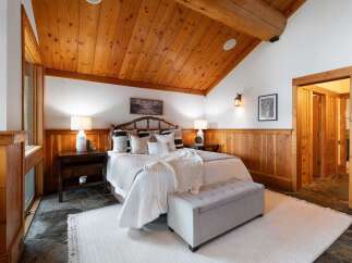 Experience rustic charm in this inviting bedroom, featuring a vaulted wood-paneled ceiling and a cozy bed adorned with plush pillows.