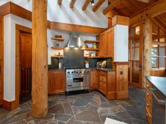 Experience rustic charm in this spacious kitchen, featuring warm wooden cabinetry and exposed beams that create a cozy, lodge-like atmosphere.