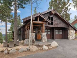 Experience rustic charm in this mountain retreat featuring a grand log-accented entrance and a natural stone facade.