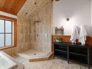 Experience luxury in this spacious bathroom featuring a walk-in shower with elegant travertine tile and a built-in bench.