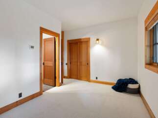Step into this inviting room featuring a warm wooden door and closet doors, complemented by a cozy blanket in a basket.